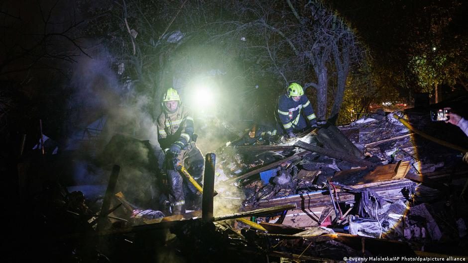 People look at a crater left by a Russian missile strike in a residential neighborhood in Kyiv, Ukraine.