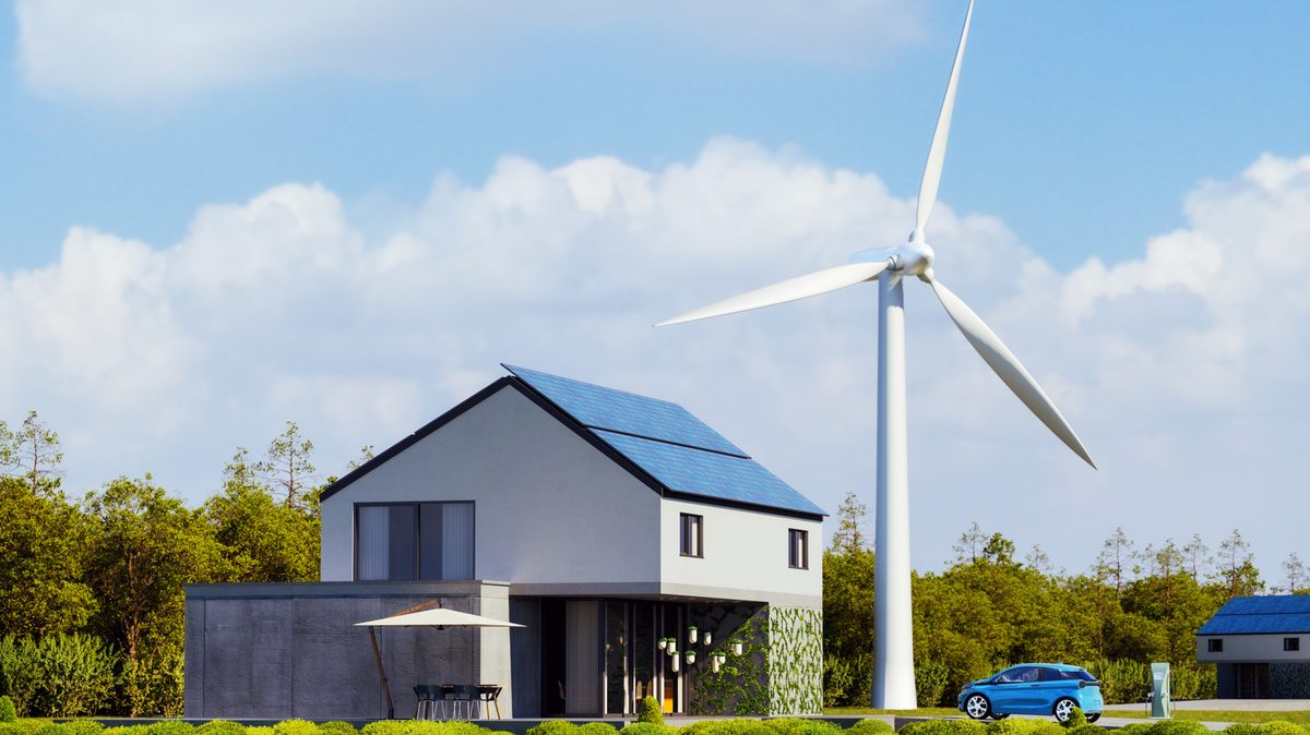 Primer pla d'una petita turbina eòlica residencial instal·lada al costat d'una casa.