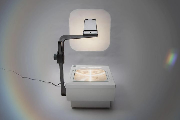 Un retroprojector clàssic il·luminant una pantalla en una aula.