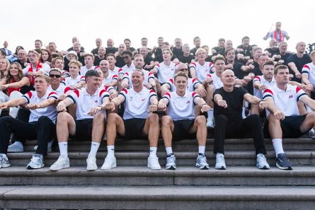 Norway’s men’s football team sits on stone steps with supporters, fists clenched