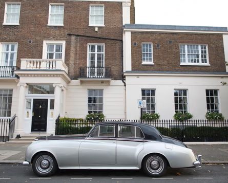 A vintage Rolls-Royce Silver Cloud is parked outside a Belgravia townhouse