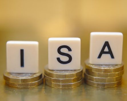 Dice spelling “Isa” sit atop stacks of coins against a blurred golden background