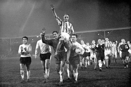 Sir Stanley Matthews is chaired off the pitch, arms raised, as players applaud in the mist
